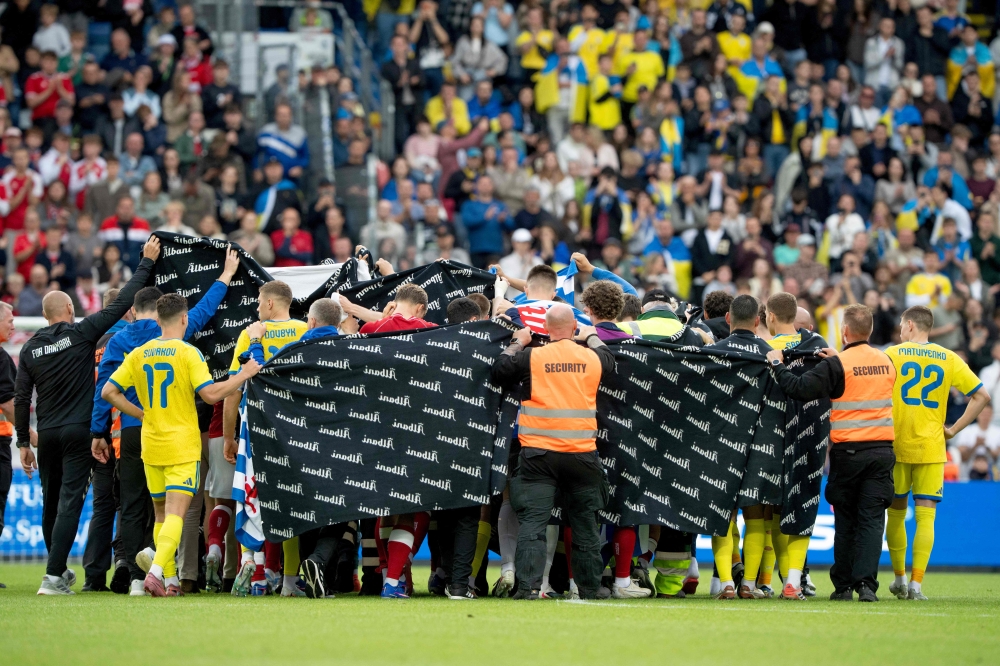Denmark's and Ukraine's players huddle to accompany Christian Eriksen to a waiting ambulance during the football international friendly match between Denmark and Ukraine at Odense Stadium in Denmark, on June 7, 2026. (Photo by Bo Amstrup / Ritzau Scanpix / AFP)