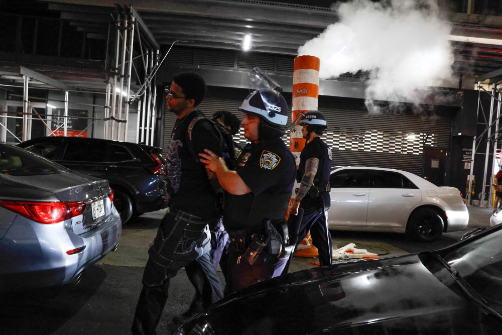 NYPD officers arrest a man after the New York knicks defeated the San Antonio Spurs in Game 5 of the NBA Finals to win the series, in New York, on June 14, 2026.
(Photo by kena betancur / AFP)