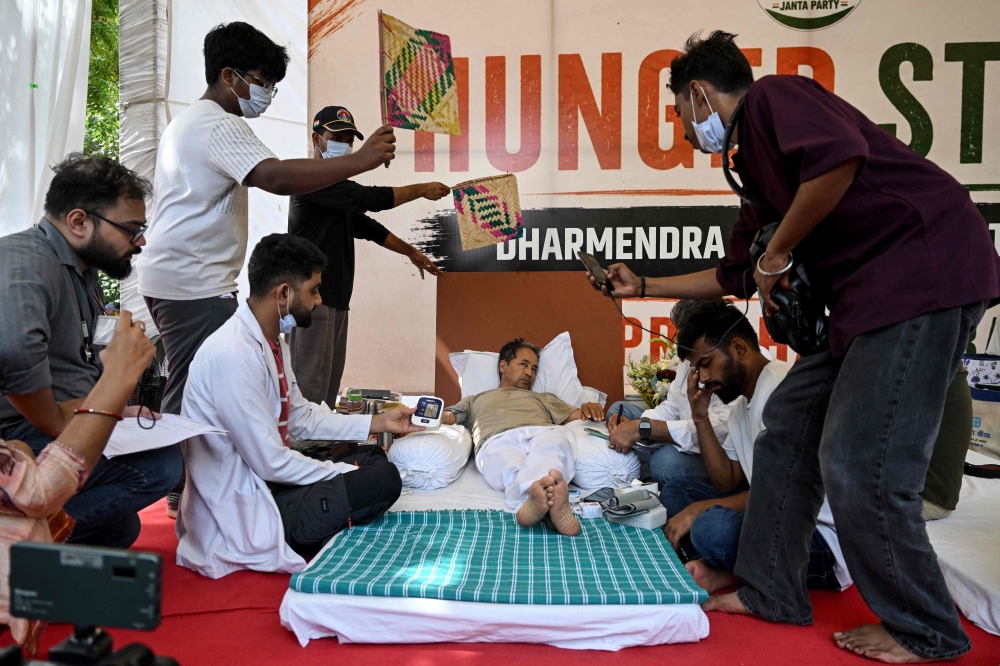 Cockroach Janta Party (CJP) founder Abhijeet Dipke (2R) reacts as doctors check activist Sonam Wangchuk vital signs during his hunger strike in New Delhi on July 15, 2026, demanding the resignation of India Education Minister Dharmendra Pradhan over alleged examination irregularities. (Photo by Arun SANKAR / AFP)
 
