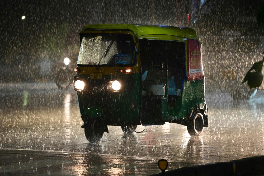 Commuters ride along a street during rainfall in Ahmedabad on July 18, 2026. (Photo by Shammi MEHRA / AFP)