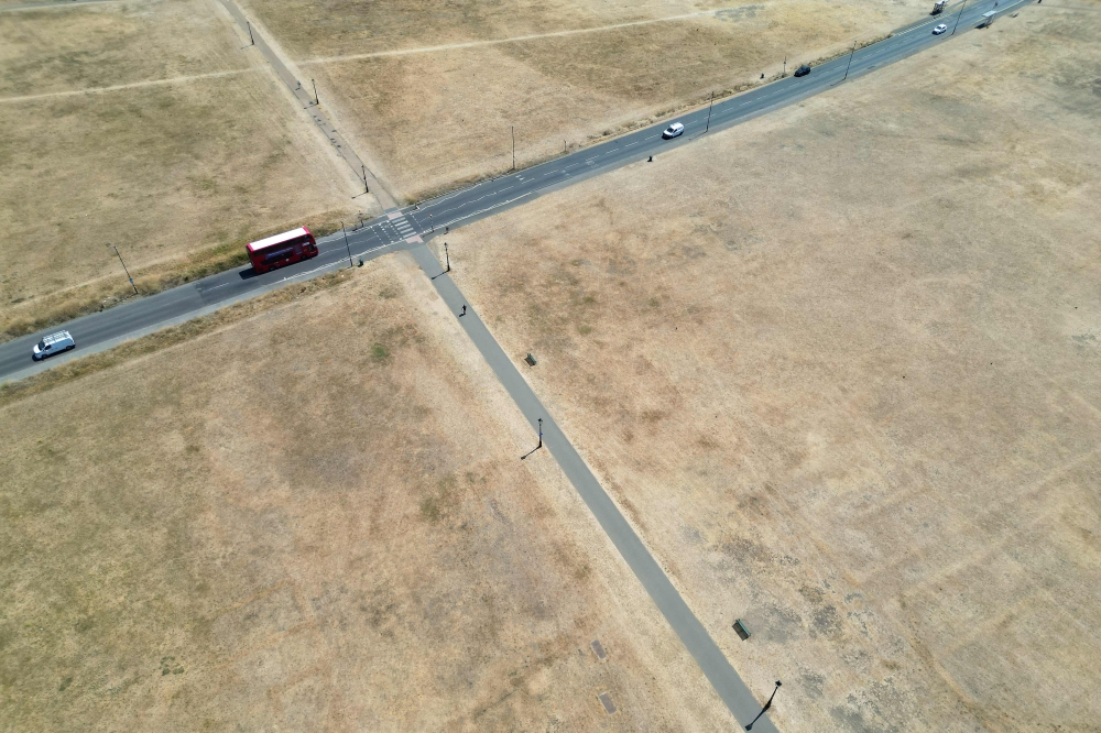 This aerial image shows a red London bus driving past the scorched grass on Blackheath in south east London, on July 29, 2026. (Photo by Justin Tallis / AFP)