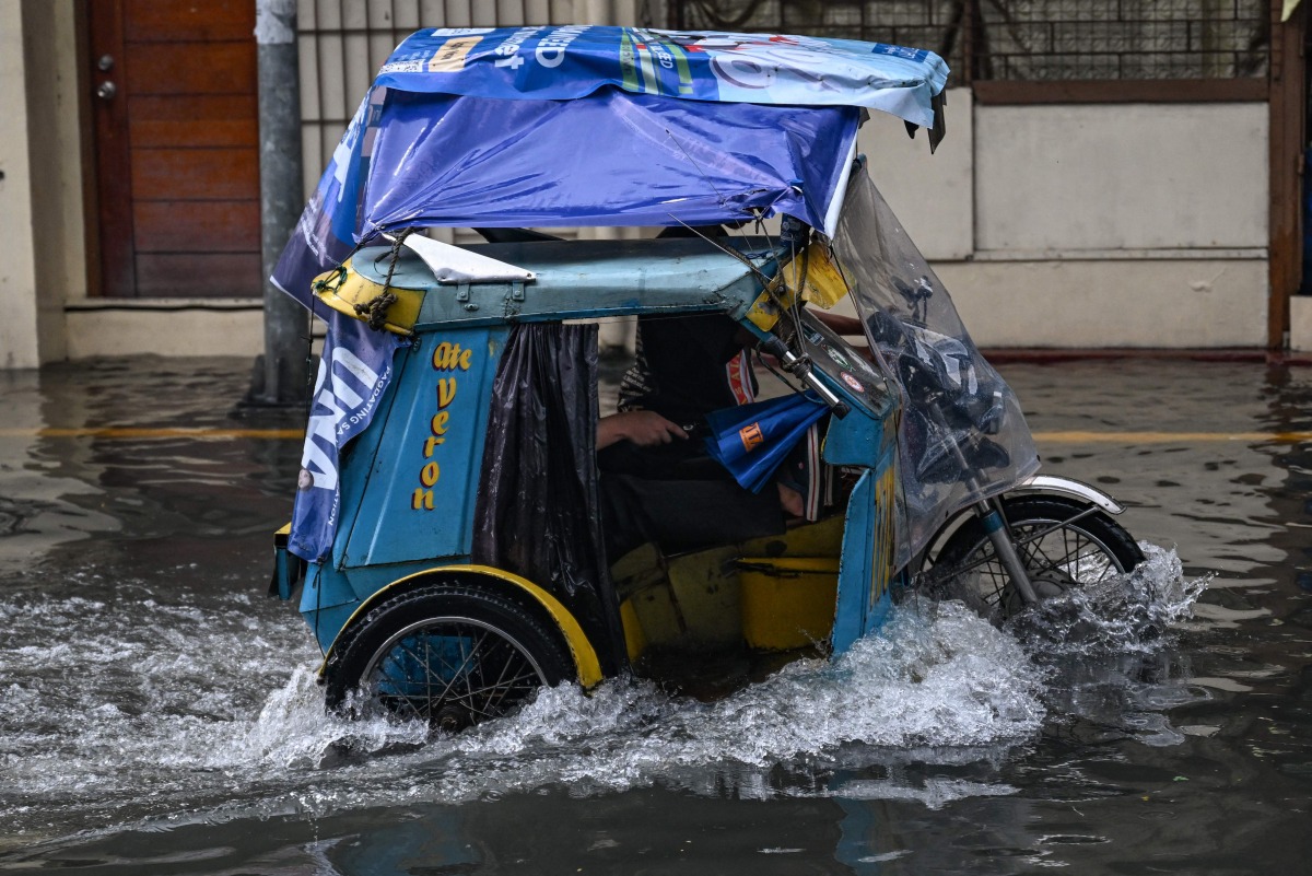 A tricycle wades through a flooded street due to heavy rains brought by the southwest monsoon in Manila on August 9, 2026. (Photo by Jam STA ROSA / AFP)