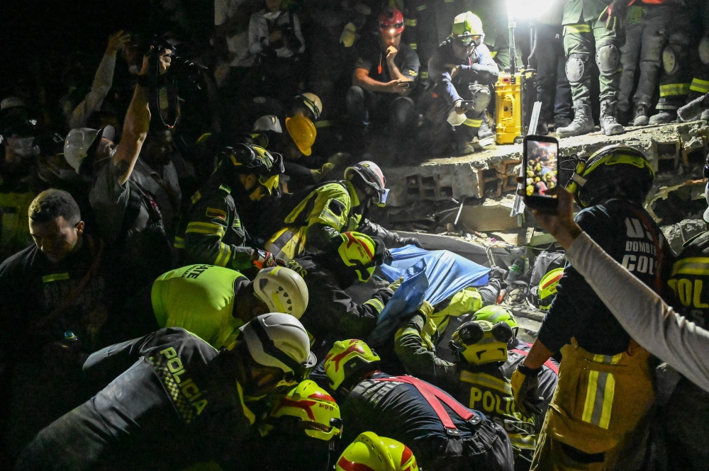 Firefighters and rescue teams carry survivor Daniela Andrea Largo Sanchez out of the rubble of a collapsed building after an earthquake in Pereira, Colombia on August 11, 2026.  (Photo by David SALAZAR / AFP)