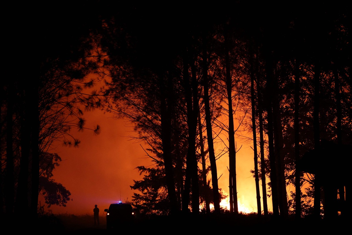 Firefighters battle a wildfire in the Landes forest in Luglon, south-western France, on August 13, 2026. Photo by ROMAIN PERROCHEAU / AFP
