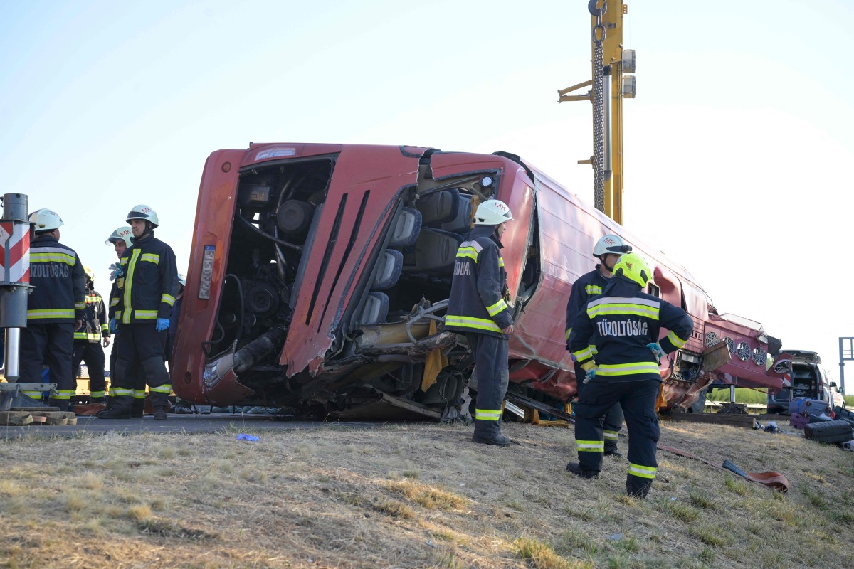 Rescue workers and other officials work at the wreckage of an overturned Polish tourist bus on the M3 motorway near Mezokeresztes, about 150 km east of the Hungarian capital Budapest, on August 16, 2026. Photo by Zoltan MATHE / MTI / AFP