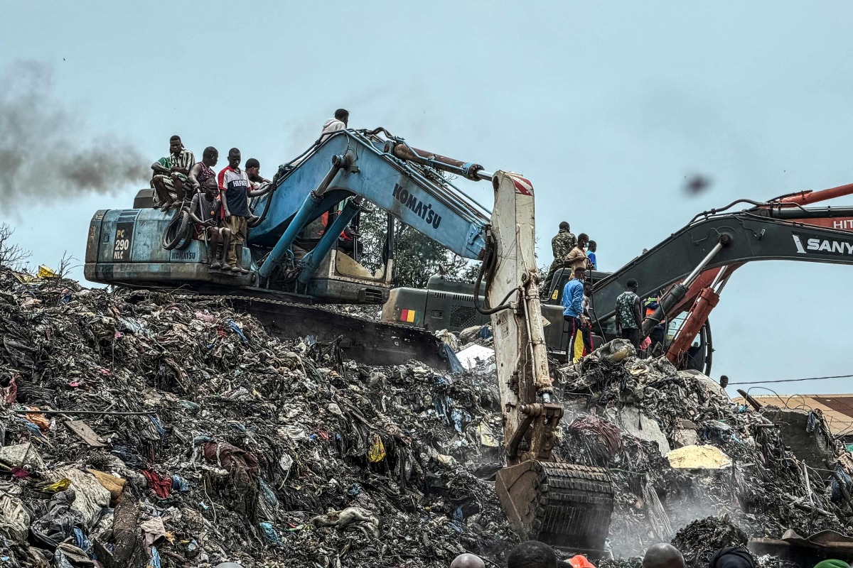 Residents and rescuers use an excavator to search for bodies after a landslide struck the Dar es Salaam dumpsite overnight in Conakry on August 23, 2026. (Photo by AFP)