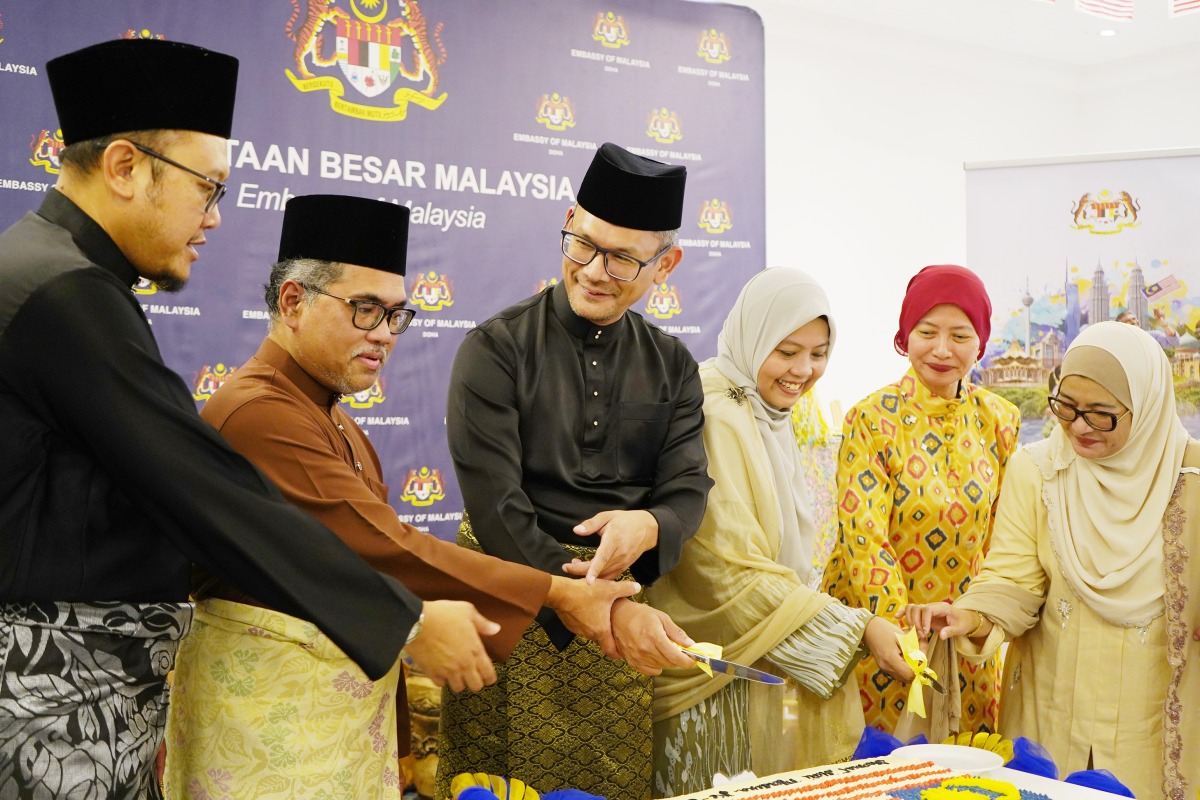 Ambassador of Malaysia H E Faizal Razali with officials and community members cutting the cake.