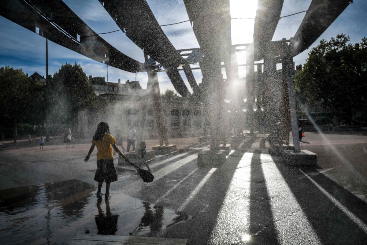 Pedestrians walk through water sprays on Place Bellecour during a heatwave in Lyon, central France on September 2, 2026. (Photo by OLIVIER CHASSIGNOLE / AFP)