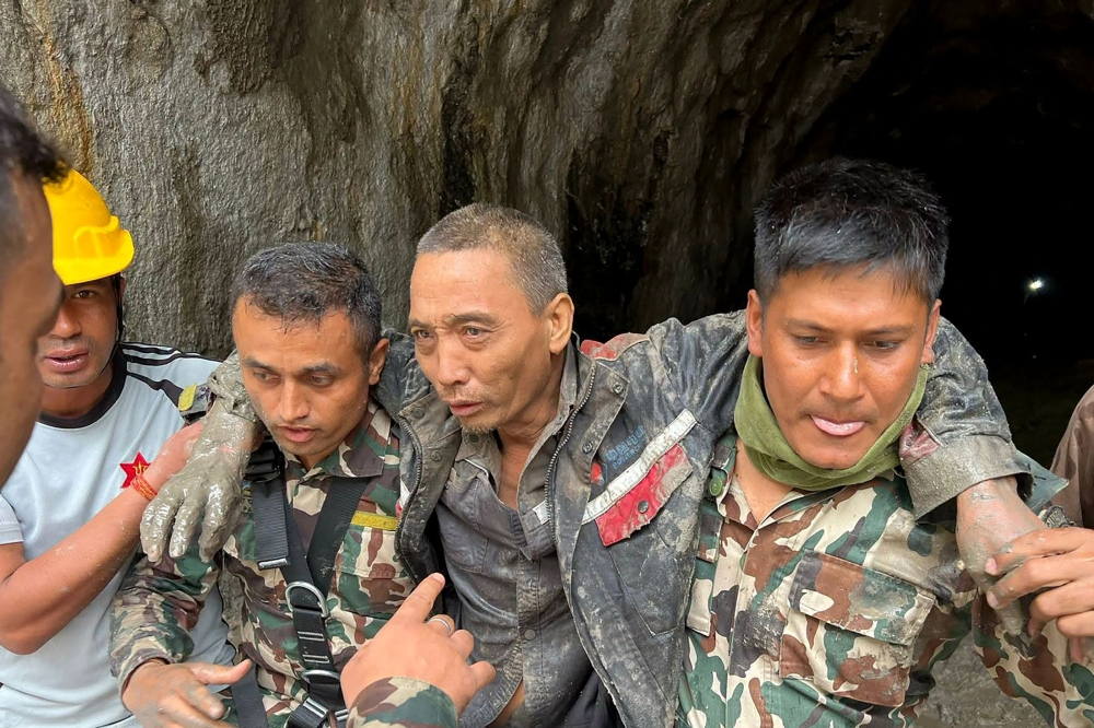 This handout photograph taken and released on September 5, 2026 via the Facebook page of Nepal Army shows security personnel carrying a Chinese national (2R) rescued from the Audit Tunnel 4 of the Upper Trishuli-1 Hydropower Project site in Nepal's Rasuwa district. (Photo by Handout / Nepal Army Facebook Page / AFP)