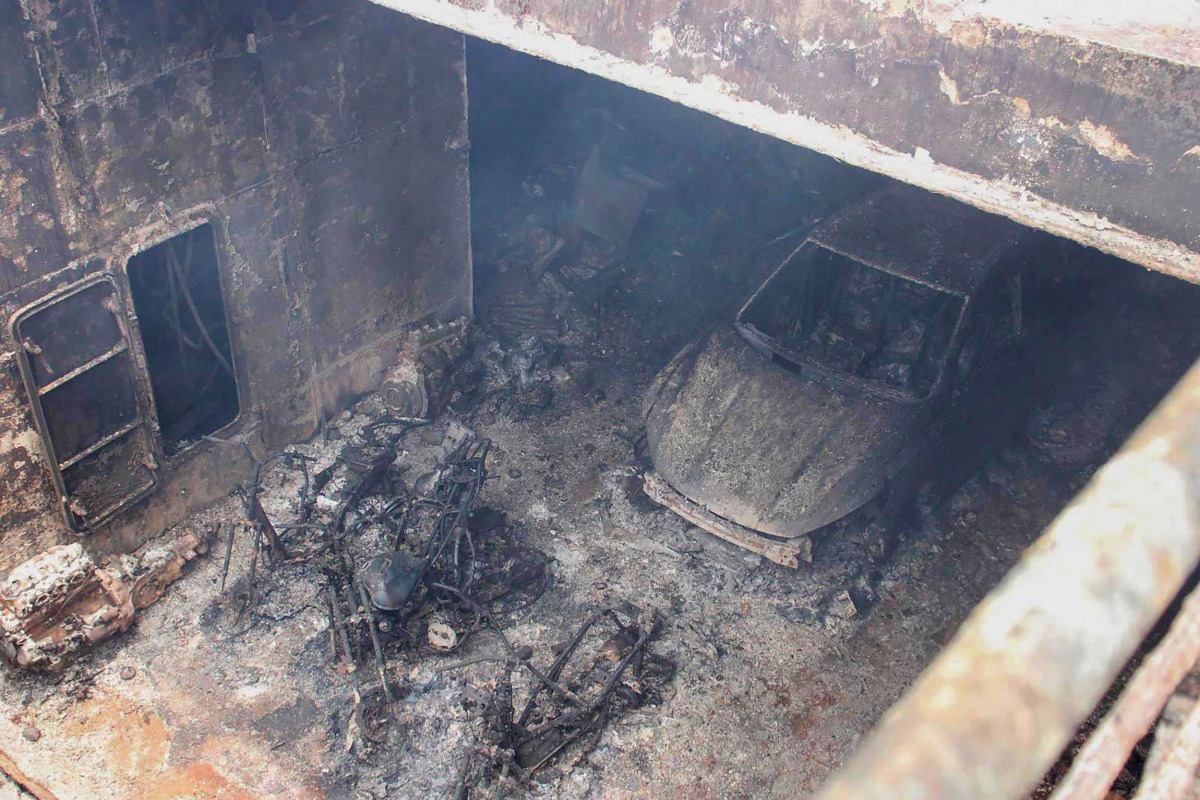 This handout photo taken on September 11, 2026 and released by the Philippine Coast Guard (PCG) shows a burnt vehicle and the burnt frames of motorbikes in the cargo hull of the M/V June Aster off the shores of Coron town, Palawan province. (Photo by Handout / Philippine Coast Guard (PCG) / AFP)
