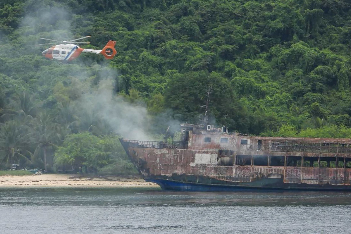 This handout photo taken on September 11, 2026 and released by the Philippine Coast Guard (PCG) shows a coast guard helicopter flying over the M/V June Aster ferry off the shore in Coron, Palawan province. (Photo by Handout / Philippine Coast Guard (PCG) / AFP)