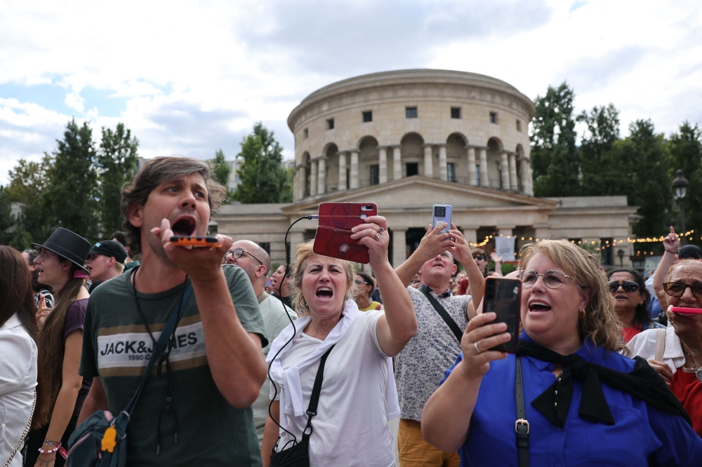 Fans of Canadian singer Céline Dion sing during a “Giant Karaoke” event in her honor in front of the La Rotonde Stalingrad monument in Paris on September 11, 2026, ahead of her concert on September 12. (Photo by Anne-Christine Poujoulat / AFP)