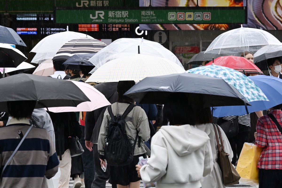 Pedestrians cross a road using umbrellas at the Shinjuku district in Tokyo on September 29, 2026, as strong Typhoon Surigae approaches Japan. (Photo by Toshifumi KITAMURA / AFP)
