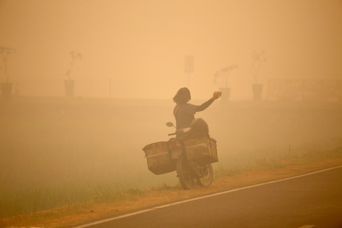 A person takes photos amid thick haze caused by forest and peatland fires in Palangka Raya, Central Kalimantan, Indonesia, Oct. 13, 2026. (Photo by Regina Safri/Xinhua)