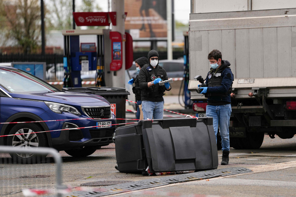 Police officers look at evidences on a site of a petrol station where a man opened fire from his car, killing one person and injuring four others according to police sources, in Trappes, Paris' suburb on October 23, 2026. Photo by Dimitar DILKOFF / AFP