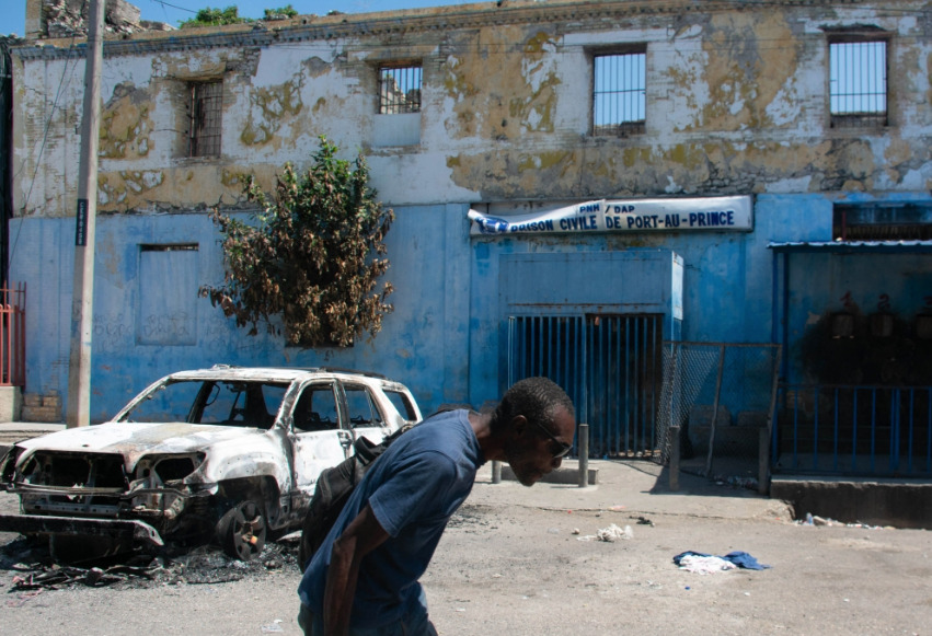 Man leaving prison area while lowering his head due to nearby gunfire in Port-au-Prince, Haiti. AFP file photo.