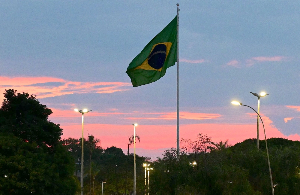 A Brazilian flag flies at sunset in Brasilia on October 24, 2026. (Photo by Pablo Porciuncula / AFP)