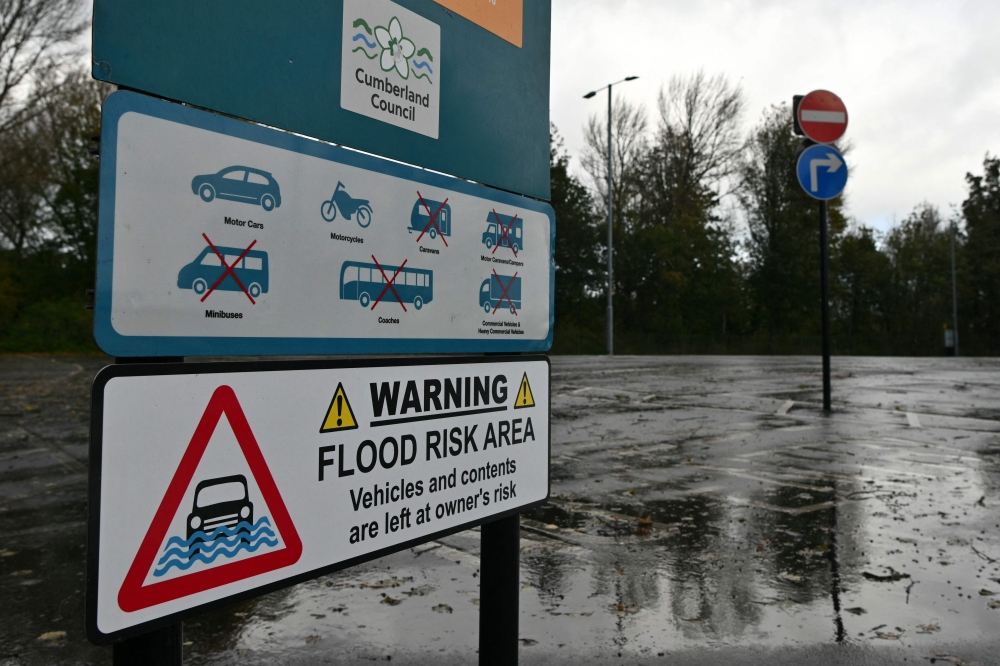 A flood warning sign is seen beside the River Eden in Carlisle in north-west England on October 25, 2026, as Storm Boelo brings strong winds and heavy rain across much of northern England. (Photo by Andy Buchanan / AFP)